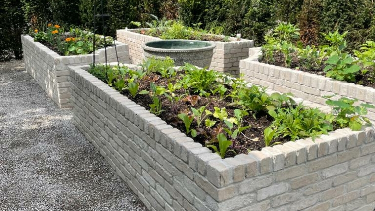 Hochbeete aus Klinkerstein mit Gemüse und Kräutern in einem naturnah gestalteten Schweizer Garten